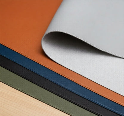 Dingo Desk vegan leather desk mat available in Charcoal, Deep Blue, Eucalyptus Green, Stone Gray and Outback Tan, with stitched edges on wooden desk