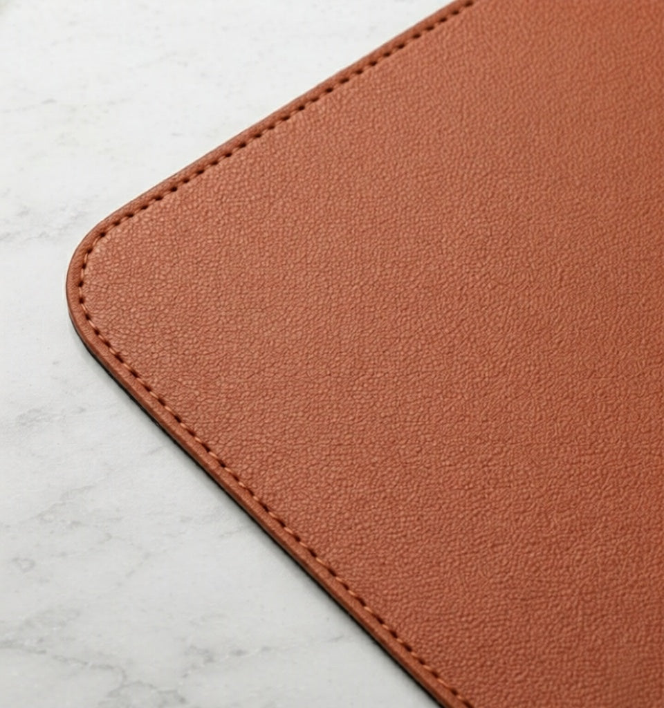 Close-up of outback tan vegan leather desk mat corner showing textured surface and stitched edge.